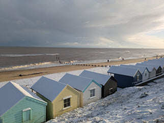 A snowy photograph of Southwold beach and beach huts