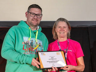Two people holding an award certificate on stage.